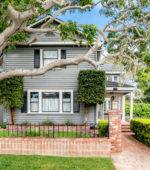 Blue historic craftsman home with brick wall and oak tree in Pacific Grove, CA